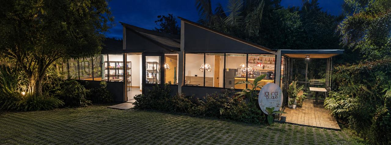 Fachada de Laura Duque Design al anochecer, con el letrero iluminado junto a la vía